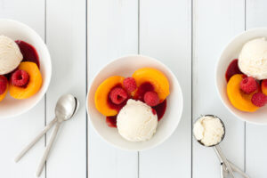 Bowls filled with Vanilla Ice Cream, Peaches and Raspberry Sauce